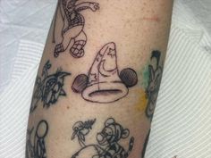 a person with tattoos on their legs and arms, has a wizard hat in his hand