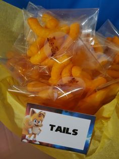 there is a plastic bag full of tiny oranges with tails on them and a sign that says tails