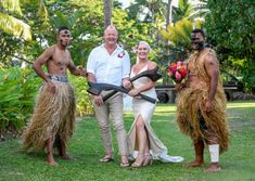 a group of people standing around each other in grass skirts and holding large sticks on their heads