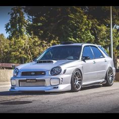 a white subarunt parked on the side of a road next to some trees