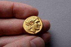 a gold coin with a man's head on it in the palm of his hand