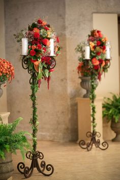 three tall vases with flowers and candles on them