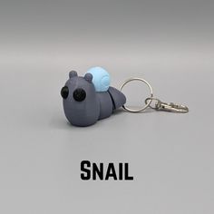 a small plastic animal keychain with the word snail on it's side