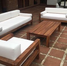 some white couches sitting on top of a brick floor next to a table and chairs