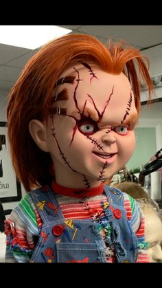 a doll with red hair and blood on it's face, wearing overalls