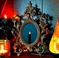 a mirror sitting on top of a wooden table next to a candle and some candles