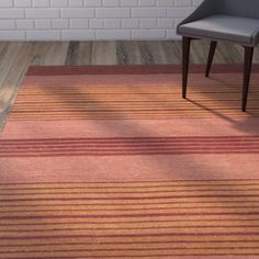 a chair sitting on top of a wooden floor next to a red and orange rug