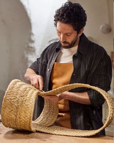 a man in an apron is working on a piece of woven material with a rope