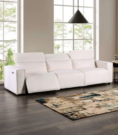 a white couch sitting on top of a hard wood floor next to a rug and window