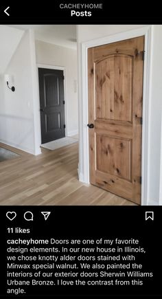 an open door in the middle of a room with hardwood floors and white walls, next to a black door