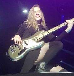 a woman sitting on top of a stage holding a guitar