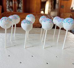 cake pops with sprinkles on them sitting on a table