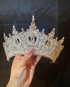 a hand holding a tiara in front of a black background