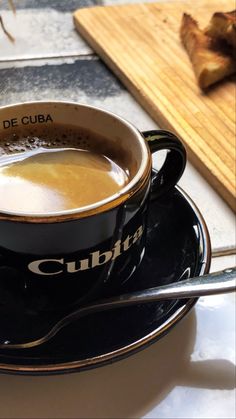 a cup of coffee sitting on top of a saucer next to a wooden cutting board