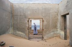 a person standing in the middle of a room with sand on the ground and an open door