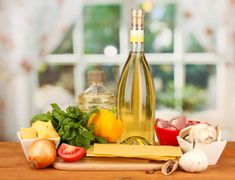 a bottle of wine sitting on top of a wooden table next to vegetables and cheese