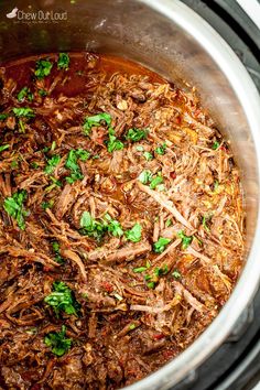 shredded meat in a pot with parsley on top, ready to be cooked for the slow cooker