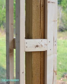 a close up of a wooden door frame with wood slats on the outside and grass in the background