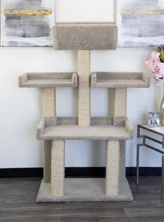 a cat tree in the corner of a room next to a vase with flowers on it