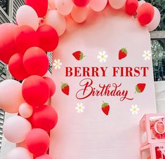 a sign that says berry first birthday surrounded by balloons