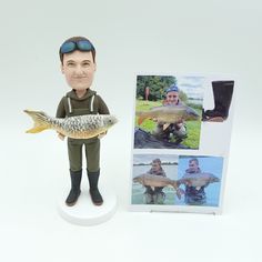 a bobble head figure holding a fish in front of a card and photo frame