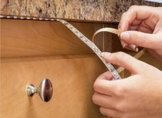 a person holding a pair of scissors next to a drawer with tape on the handle