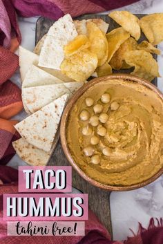 taco hummus with tortilla chips on the side and text overlay