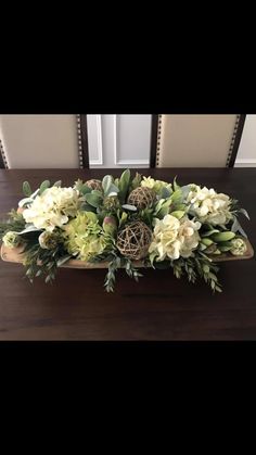 a wooden tray with flowers and greenery in it