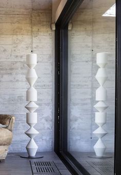 a living room filled with furniture next to a tall white vase on top of a hard wood floor