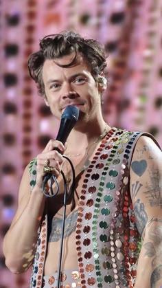 a man with tattoos on his chest holding a microphone