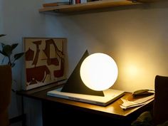 a lamp sitting on top of a wooden table next to a book case and chair