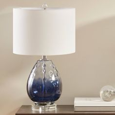 a blue glass table lamp sitting on top of a night stand