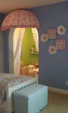 a child's bedroom with blue walls and pink flowers on the ceiling, along with a white footstool