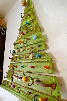 a green christmas tree made out of old door knobs and hooks on a wall