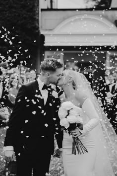 a bride and groom kiss as confetti falls around them