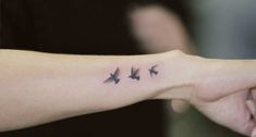 a woman's arm with three birds tattooed on the left side of her arm