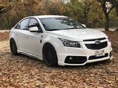 a white car is parked in the leaves