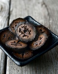 a black plate topped with chocolate cookies on top of a wooden table