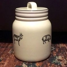 a white jar with animals on it sitting on a carpeted floor next to a wall