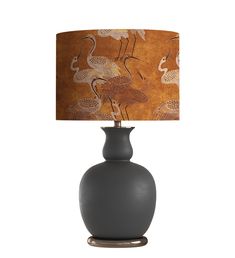 a lamp that is on top of a table next to a vase with a bird design on it