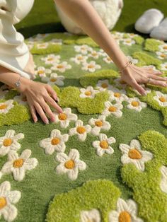 a woman is touching the ground with her hand on a green and white flowered rug