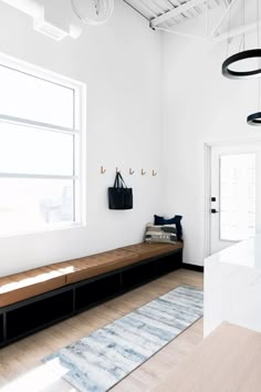 a white room with a bench, rug and light fixture hanging from it's ceiling