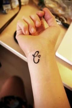 a woman's arm with a small tattoo on her left wrist and the letter c in the middle