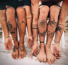 four people with tattoos on their legs are standing next to each other and holding hands