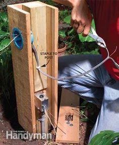 a man is working on an electrical box in the garden with wires attached to it