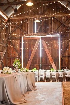 the inside of a barn with tables and chairs set up for a wedding reception at night