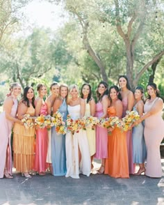 a group of women standing next to each other wearing dresses and holding bouquets in their hands