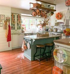 a kitchen filled with lots of counter top space and hanging utensils on the ceiling