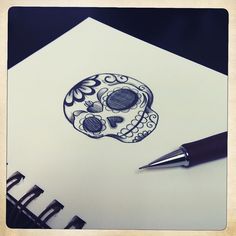 a drawing of a skull on paper next to a pen