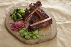 some meat and broccoli on a cutting board with a white cloth behind it